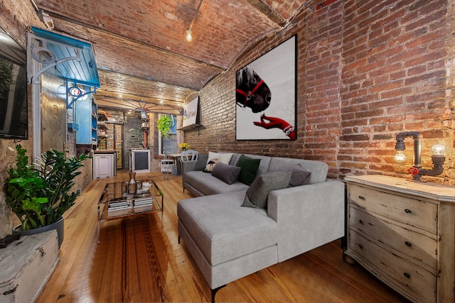 living room featuring lofted ceiling, brick ceiling, brick wall, and hardwood / wood-style flooring