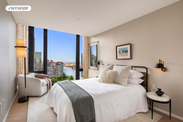 bedroom featuring light hardwood / wood-style floors, floor to ceiling windows, and a water view