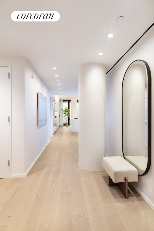 hall featuring baseboards, light wood-type flooring, and recessed lighting