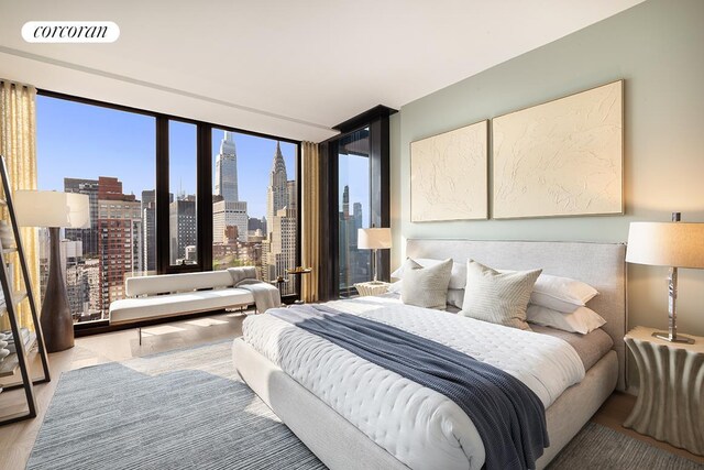 bedroom with a view of city, visible vents, and a wall of windows