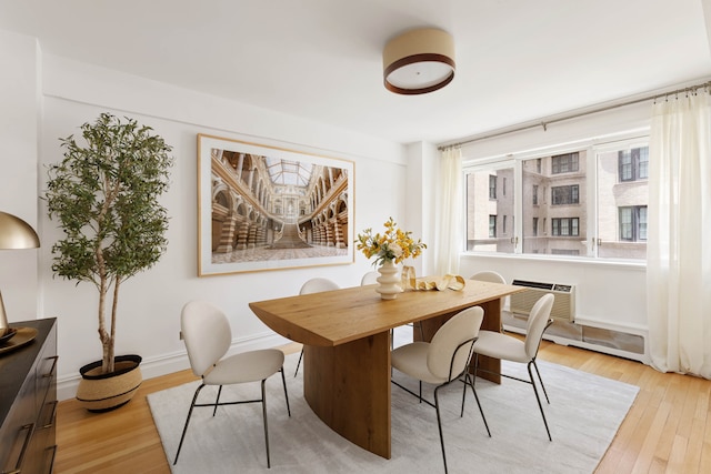 dining room with light wood-type flooring and a wall unit AC