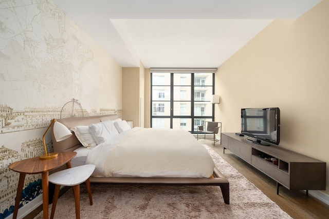 bedroom with expansive windows and dark wood-type flooring