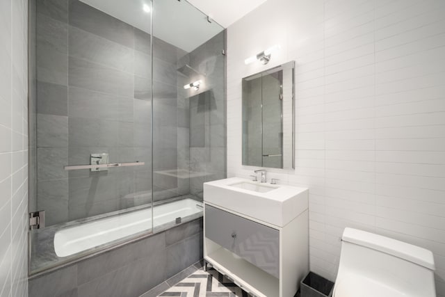 bathroom featuring tiled shower / bath combo, toilet, tile walls, and vanity