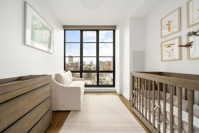 bedroom featuring a view of city, baseboards, and wood finished floors