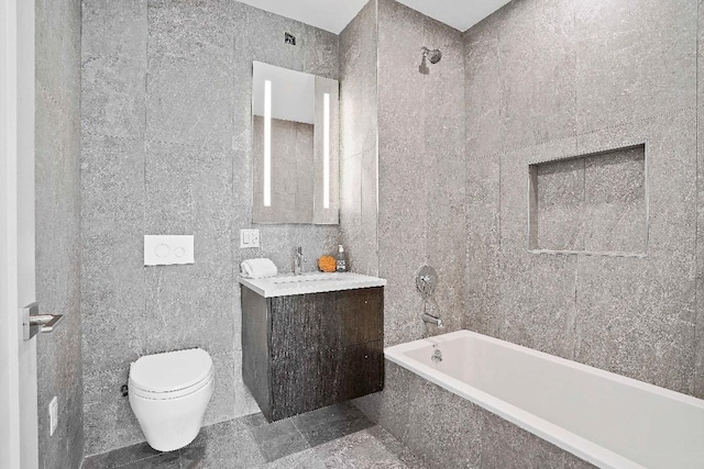 full bathroom featuring tiled shower / bath, tile walls, vanity, and toilet