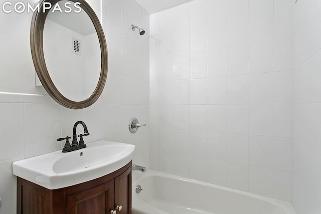 bathroom with tile walls, vanity, backsplash, and tiled shower / bath