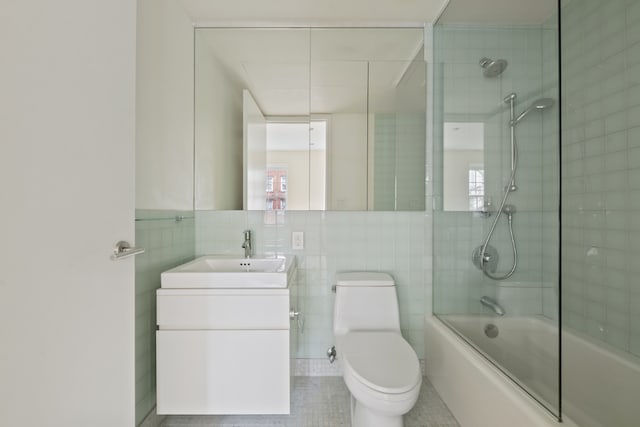 full bathroom with vanity, toilet, shower / bath combination with glass door, and tile walls