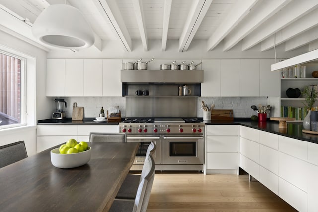 kitchen with range with two ovens, white cabinetry, and beamed ceiling