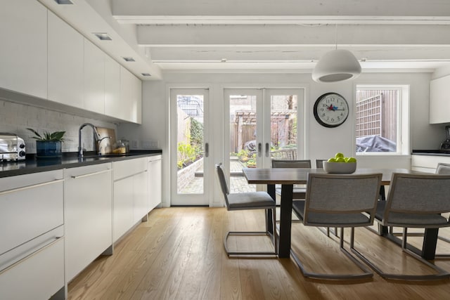 dining room featuring beamed ceiling, light hardwood / wood-style floors, sink, and french doors