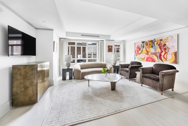 living room featuring a tray ceiling, visible vents, baseboards, and wood finished floors