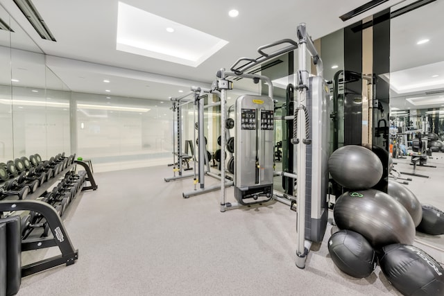 workout area with a tray ceiling and recessed lighting