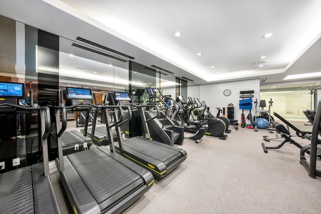 workout area featuring a raised ceiling and recessed lighting