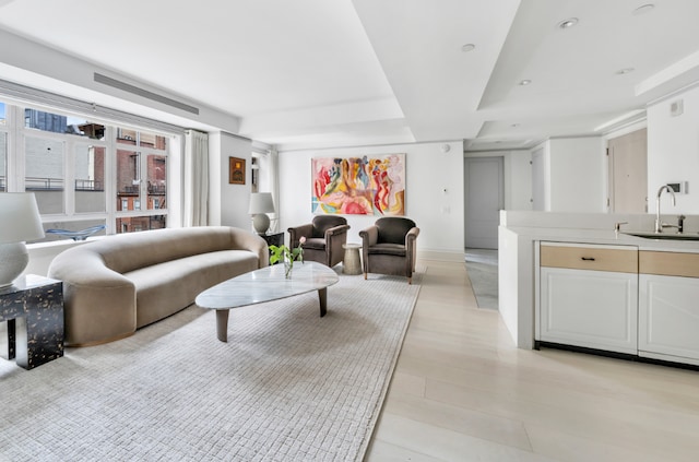 living room with a raised ceiling and sink