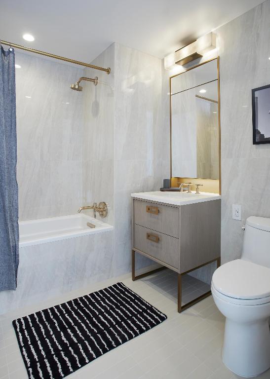 full bathroom with toilet, tile patterned flooring, shower / bath combination with curtain, tile walls, and vanity