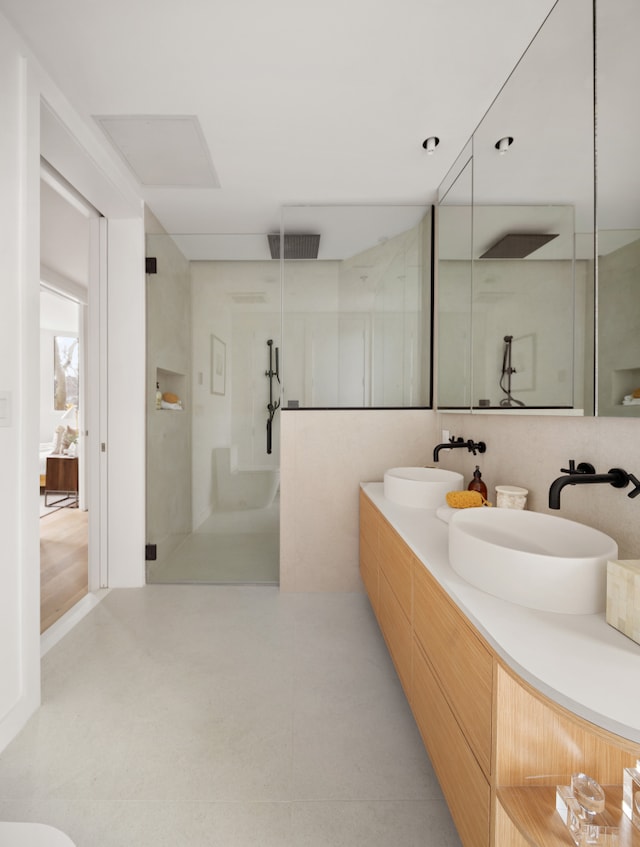 bathroom featuring a stall shower, a sink, ensuite bath, and double vanity