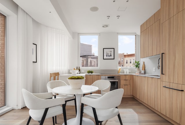 dining area featuring light wood-type flooring and expansive windows