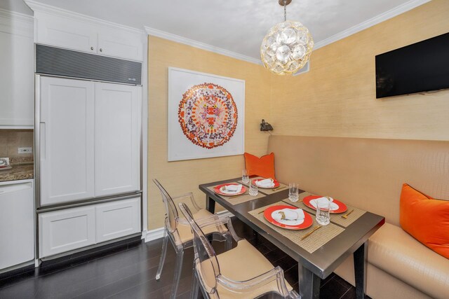 dining space with dark wood-type flooring, ornamental molding, and a chandelier