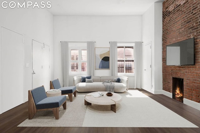 living room featuring a high ceiling, dark wood-type flooring, and a fireplace