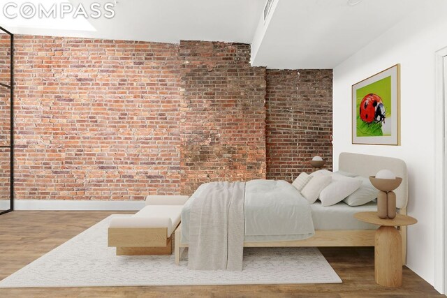 unfurnished living room featuring a towering ceiling, dark hardwood / wood-style floors, and brick wall