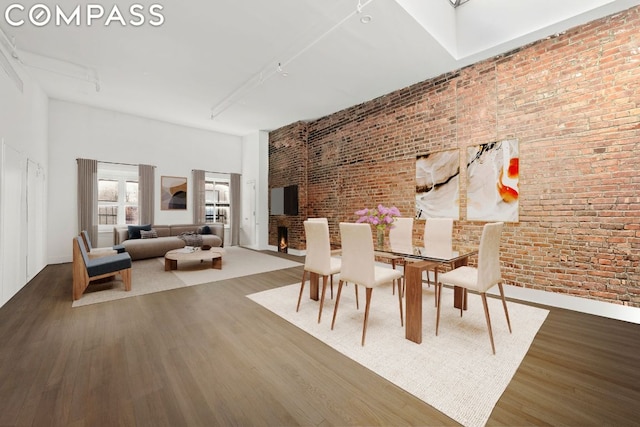 bedroom featuring dark wood-type flooring, brick wall, and a fireplace