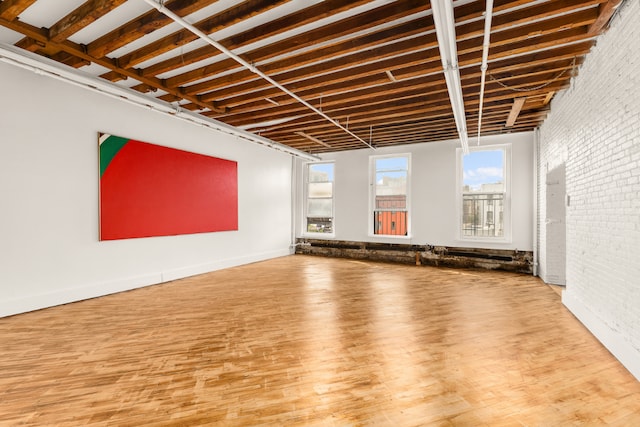 spare room with hardwood / wood-style flooring and brick wall