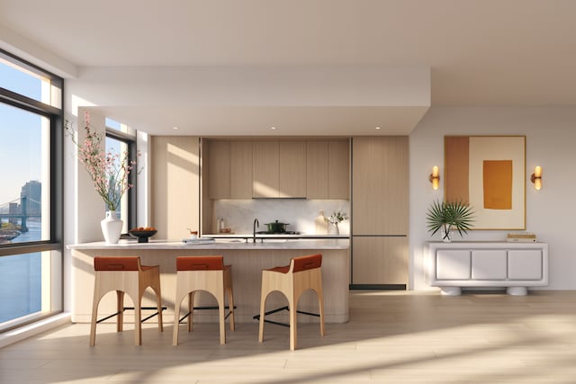 kitchen with modern cabinets, a kitchen bar, backsplash, floor to ceiling windows, and light wood finished floors