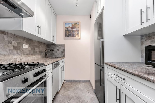 kitchen with a sink, white cabinetry, stainless steel appliances, wall chimney range hood, and decorative backsplash