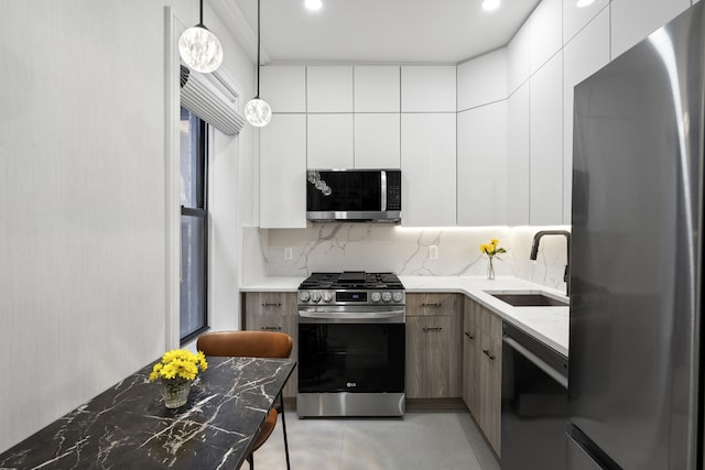 kitchen with light stone counters, stainless steel appliances, a sink, white cabinetry, and modern cabinets