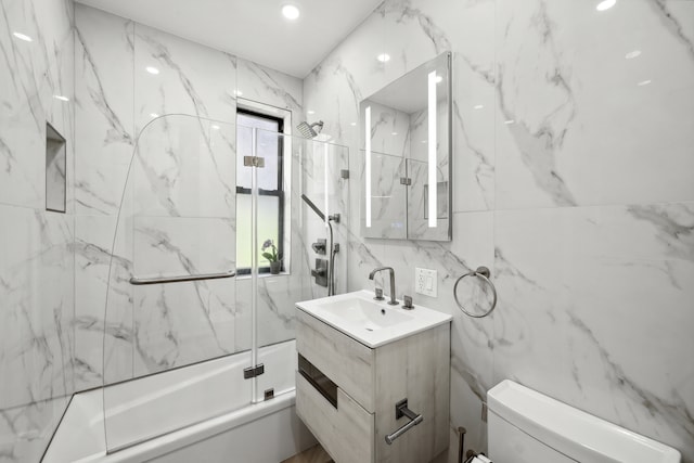 325 E 80th St Unit 4H, New York City, NY 10075 - full bathroom featuring bath / shower combo with glass door, vanity, toilet, and tile walls