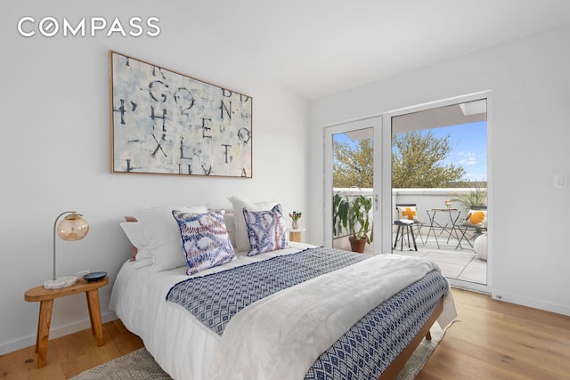 bedroom featuring vaulted ceiling, wood finished floors, baseboards, and access to outside