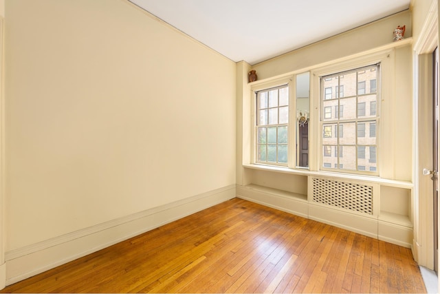 empty room with wood-type flooring, baseboards, and lofted ceiling