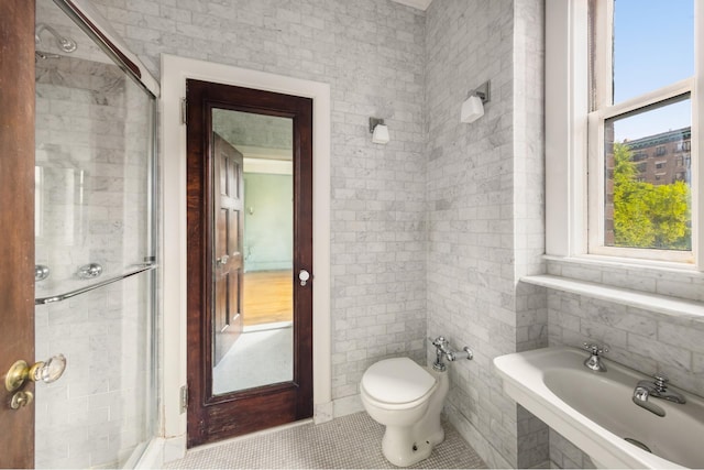bathroom with a bidet, tile patterned flooring, toilet, a shower stall, and tile walls