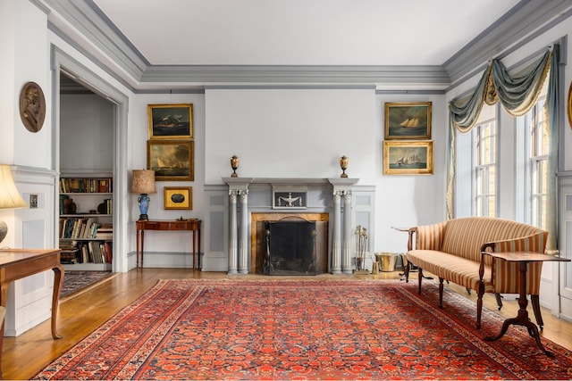 sitting room with a premium fireplace, crown molding, and wood finished floors