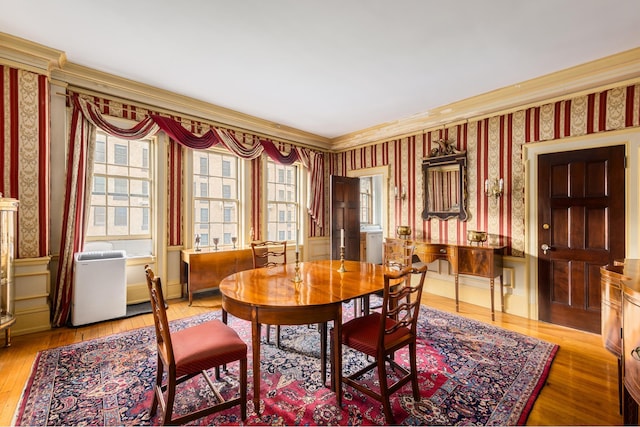 dining room featuring wood-type flooring, washer / dryer, wallpapered walls, and crown molding