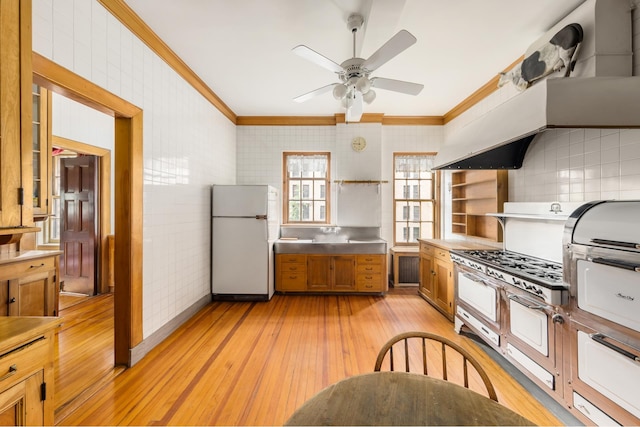 kitchen featuring crown molding, open shelves, stainless steel counters, and freestanding refrigerator