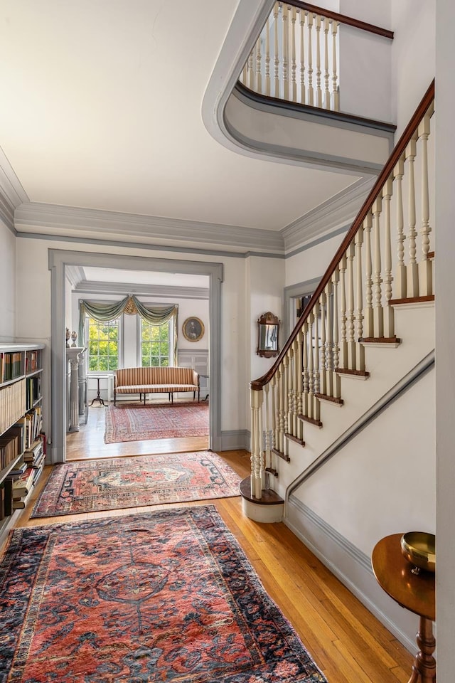 foyer featuring stairway, baseboards, ornamental molding, and wood finished floors