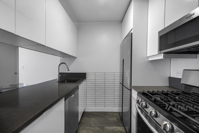 kitchen with modern cabinets, a sink, white cabinets, and appliances with stainless steel finishes