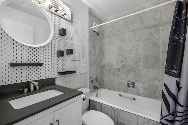 bathroom featuring toilet, vanity, tiled shower / bath, and tile walls
