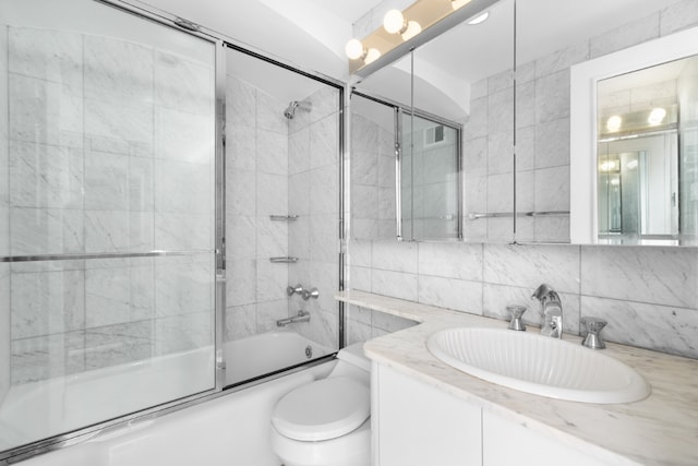 full bathroom with combined bath / shower with glass door, tile walls, decorative backsplash, vanity, and toilet