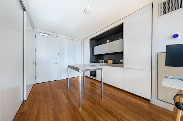 kitchen with white cabinetry, visible vents, open shelves, and wood finished floors