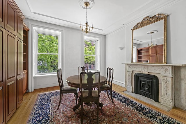 dining area with crown molding, light wood-type flooring, a chandelier, and a healthy amount of sunlight