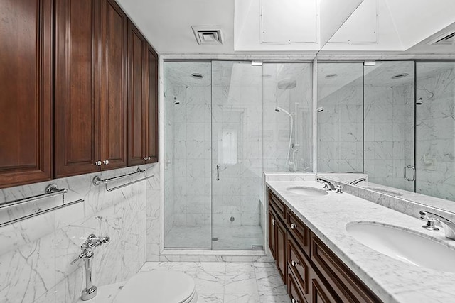 bathroom featuring a sink, a stall shower, double vanity, and marble finish floor