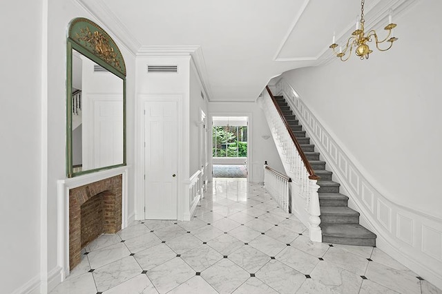 tiled foyer entrance with visible vents, ornamental molding, stairs, an inviting chandelier, and a wainscoted wall