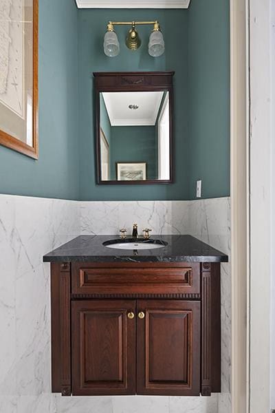 bathroom featuring tile walls, ornamental molding, and vanity