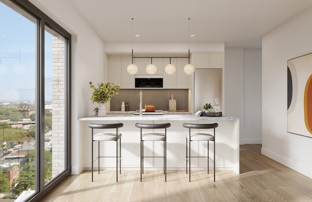 kitchen featuring decorative light fixtures, kitchen peninsula, light wood-type flooring, and white cabinets