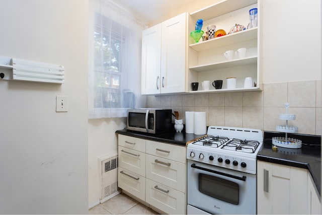 kitchen with dark countertops, visible vents, open shelves, white gas stove, and stainless steel microwave