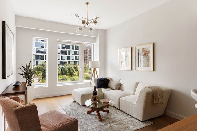 living room with an inviting chandelier, baseboards, and wood finished floors