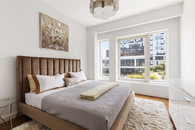 bedroom featuring baseboards, light wood-type flooring, and an inviting chandelier