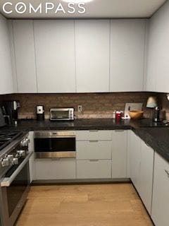 kitchen featuring white cabinetry, tasteful backsplash, stainless steel appliances, and light hardwood / wood-style flooring