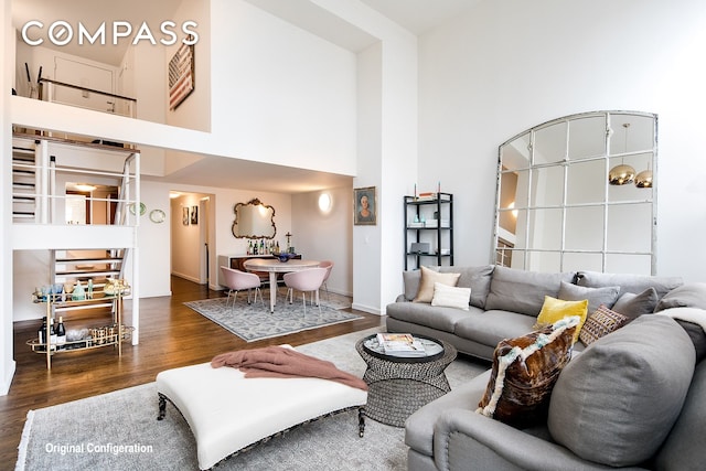 living room featuring dark wood-style floors, a towering ceiling, and baseboards